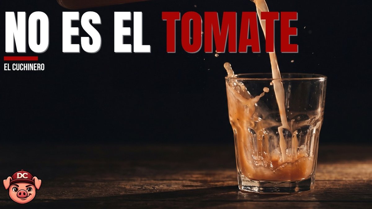Vaso de gazpacho andaluz denso y opaco que vela el cristal, junto a verduras y a